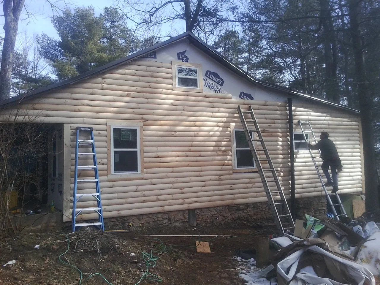 Ladders set against fresh log siding during an exterior remodel in Clayton